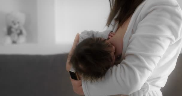 Mother is breastfeeding her newborn baby in the nursery. Mom cradles a infant. — стокове відео