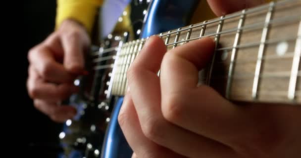 Мужчина-гитарист, играющий пальцами с плектромом на голубой электрогитаре. — стоковое видео