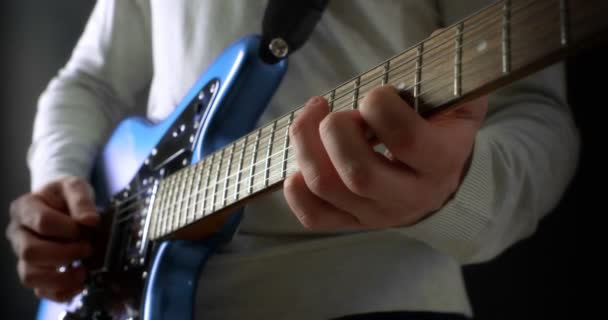 黒い背景の灰色のジャンパーの創造的な音楽家は電気ギターを演奏する. — ストック動画