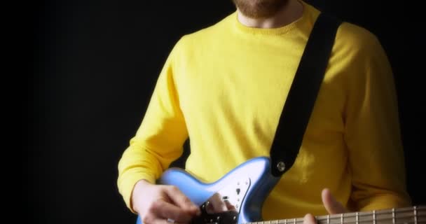 Muž kytarista ve žlutém jumper hraje elektrickou kytaru na černém pozadí — Stock video