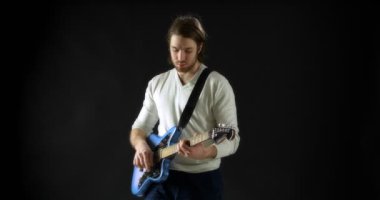 Siyah arka plandaki gri kazaklı yaratıcı müzisyen elektro gitar çalıyor.. 