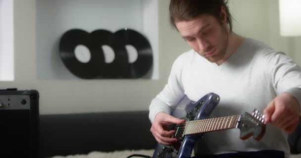 Tvůrčí hudebník v šedém jumperu ladí modrou elektrickou kytaru. — Stock video