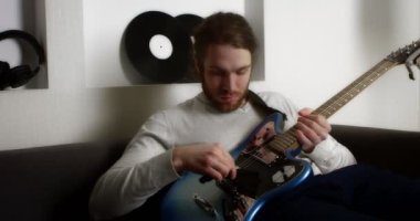Genç adam evde elektro gitar çalıyor..