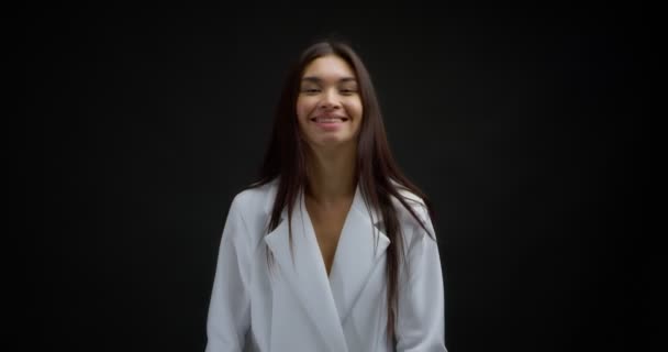 Despreocupado feliz jovem mulher sorrindo e fixando seu cabelo sobre fundo preto — Vídeo de Stock