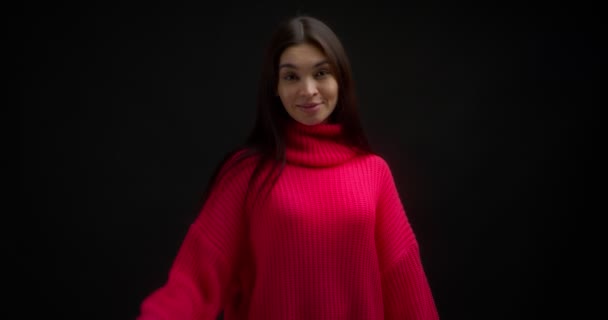 Sorrindo mulher asiática em uma camisola rosa brilhante acena sua mão. — Vídeo de Stock