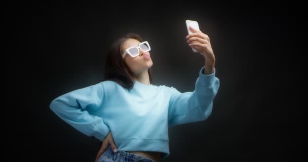 Junge Asiatin macht Gesichter vor dem Smartphone und macht dumme Selfies — Stockvideo