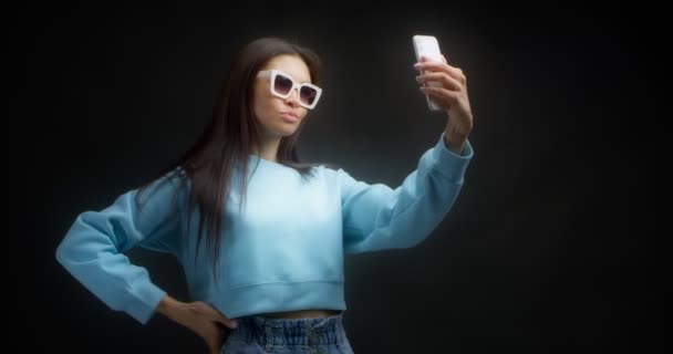 Junge Asiatin macht Gesichter vor dem Smartphone und macht dumme Selfies — Stockvideo