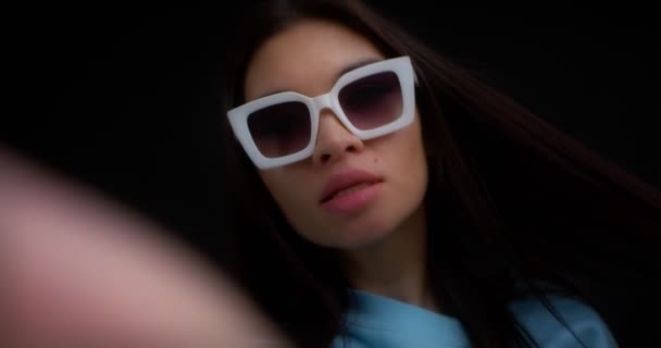 Close-up do rosto de uma morena em óculos tirando uma selfie em um smartphone. — Vídeo de Stock