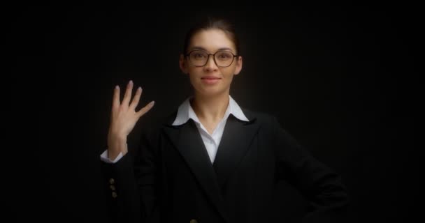 Ασιάτισσα με γυαλιά χαμογελά και δείχνει τέσσερα δάχτυλα με το δεξί της χέρι.. — Αρχείο Βίντεο