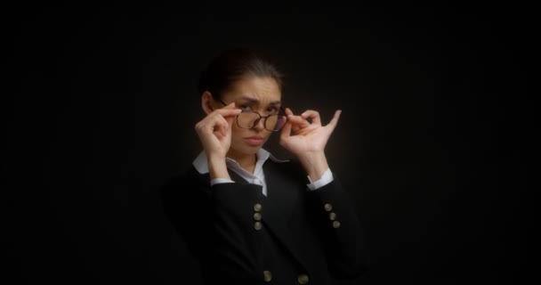 Business woman with glasses with a dissatisfied expression looks at the camera. — Stock Video