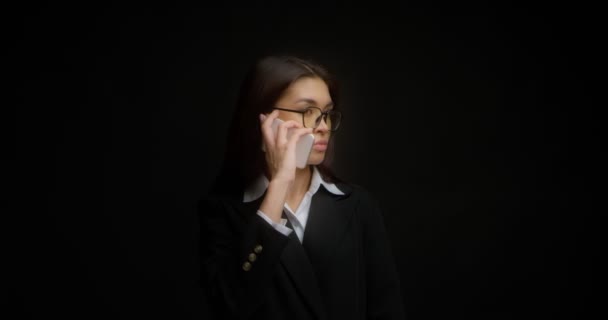 Femme d'affaires avec des lunettes et un visage sérieux parle au téléphone. — Video