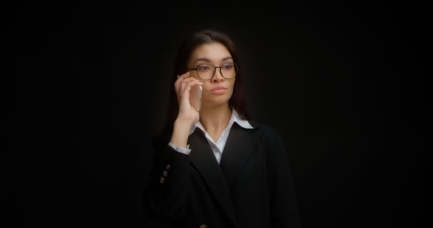 Mujer de negocios con gafas y una cara seria está hablando por teléfono. — Vídeos de Stock