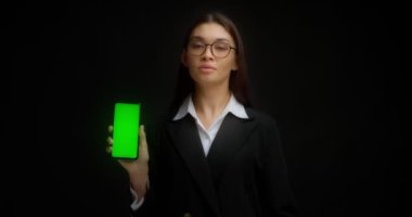 Gözlüklü iş kadını kopyalama için dikey yeşil telefon ekranı gösteriyor. ChromaKey