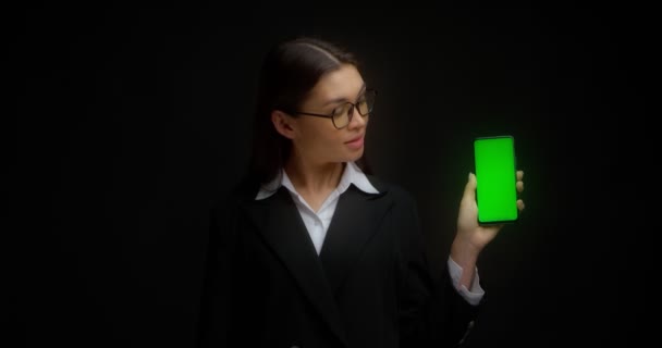 Senhora de negócios em óculos mostra tela de telefone verde vertical para copying.ChromaKey — Vídeo de Stock