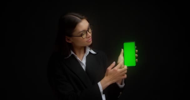 Бизнес-леди в очках показывает вертикальный зеленый экран телефона для копирования. — стоковое видео