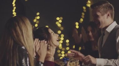 Parti ya da doğum günü kutlaması şirket ya da grupla. Neşeli bir kadın arkadaşlarıyla kucaklaşıp tokalaşıyor, doğum günü için kağıda sarılmış hediyeler alıyor ve akşam yemeğinden önce evde teşekkür ediyor..