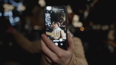 Avrupa 'da büyük bir Noel ağacının önünde selfie çekmeye çalışan bir adamın portresi. Gençler, kış tatili sezonunda dışarıda seyahat ederken anı yakalıyorlar..