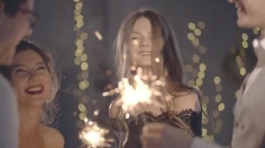 Avuç içi aydınlatma mandalına ya da ateşe yaklaşın. Tutun ve kıvılcımlar sallayın. Yılbaşını ya da Noel 'i birlikte kutlayan genç milenyum arkadaşlarının portresi. Mutluluk ya da eğlence konsepti.