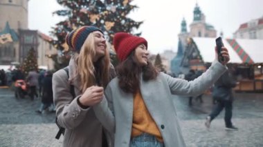 Prag 'da Xsmas meydanında selfie çeken iki blogcu kız. Arkadaşlık, tatil, Noel, blogcu, yaşam tarzı konsepti. RED kamera, 10 bit klonlama