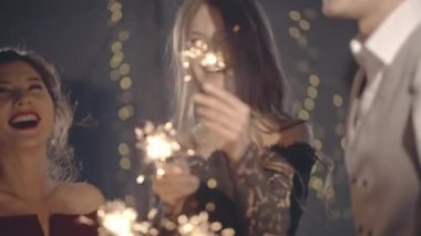 Avuç içi aydınlatma mandalına ya da ateşe yaklaşın. Tutun ve kıvılcımlar sallayın. Yılbaşını ya da Noel 'i birlikte kutlayan genç milenyum arkadaşlarının portresi. Mutluluk ya da eğlence konsepti.