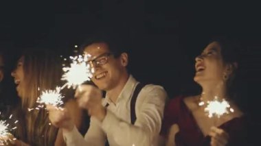 Büyük bir grup çok ırklı arkadaş ya da tanıdıklar ellerinde maytap tutuyor ve sallıyorlar. Tatili kutlayan hippiler. Partide eğlenen neşeli, mutlu bir grup insan. Yaşam tarzı kavramı.