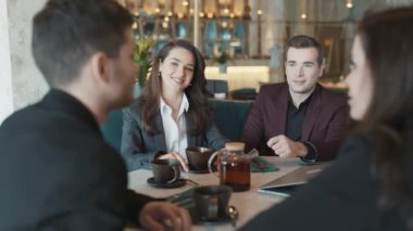 Çeşitli iş arkadaşları restoranda bir masada oturuyorlar. İş arkadaşları çalışma şartlarını tartışıyor. Takım çalışması kavramı, eğlence, takım oluşturma..