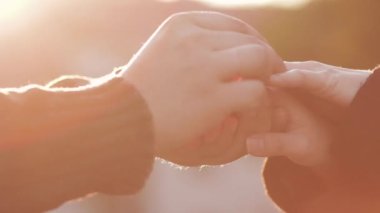 Erkek, nişan yüzüğünü kadın parmağına takıyor. Yaz akşamları aşık bir erkek ve kadın. İnsanlar kalpten konuşuyor ve sarılıyorlar. Altın güneş ve güzel günbatımında öpüşen çiftlerin silueti.