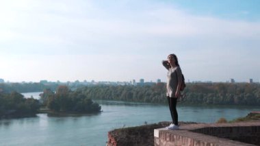 Kız turist kulenin tepesinde dinleniyor. Gülümseyen kız kamerada flört ediyor. Güzel bir kadın eski şehir sokağına gidiyor ve güneş parlıyor. Mor saçlı, seksi, stil sahibi bir kadın.