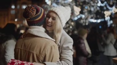 Noel yemeğinin ortasında arkadaşla buluşan güzel bir kızın portresi. Gençler tatil sezonunu dışarıda, hediyelerini paylaşarak geçiriyorlar..