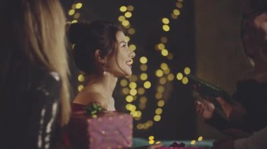 Neşeli bir kadın arkadaşlarıyla kucaklaşıp tokalaşıyor, doğum günü için kağıda sarılmış hediyeler alıyor ve akşam yemeğinden önce evde teşekkür ediyor. Parti ya da doğum günü kutlaması şirket ya da grupla.