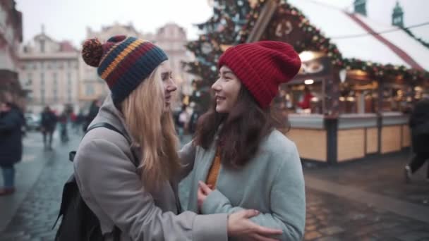Two young woman finally meet on square in european town. Girls very happy to see each other during christmas fare. Atmosphere of holidays and uniting, girls going to spend time together. — Stock Footage Two young woman finally meet on square in european town. Girls very happy to see each other during christmas fare. Atmosphere of holidays and uniting, girls going to spend time together. Royalty Free Stock Video