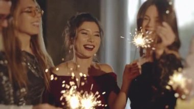 Akşamları eğlenen mutlu bir grup insan. Kapalı portre arkadaşları maytapları ellerinde tutuyorlar. Çocuklar havai fişek sallayarak, yılbaşında ya da Noel arifesinde eğlenerek kutlama yapıyor..