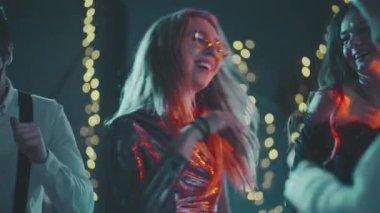 Mutlu, gülümseyen adamlar renkli ışıklarla süslenmiş evin önünde birlikte eğleniyorlar. Doğum gününde, yeni yılda, Noel 'de ya da Xmas partisinde dans eden çok ırklı genç hippi arkadaşlara yakın çekim.