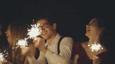 Büyük bir grup çok ırklı arkadaş ya da tanıdıklar ellerinde maytap tutuyor ve sallıyorlar. Tatili kutlayan hippiler. Partide eğlenen neşeli, mutlu bir grup insan. Yaşam tarzı kavramı.