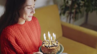 İnsanlar sosyal mesafeyi korumak için zaman harcarlar. Mutlu Asyalı çok ırklı kadın doğum günü şapkası takmış arkadaşının mum üflemesini videolu konuşma yoluyla evde covid-19 pandemisi sırasında kutluyor.