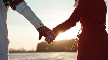 Noel zamanı randevuda olan iki kişi. Kış günbatımında eldiven takan çiftin arka görüntüsü. Aşk ve ilişki kavramı.