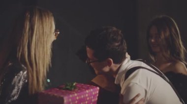 Neşeli bir kadın arkadaşlarıyla kucaklaşıp tokalaşıyor, doğum günü için kağıda sarılmış hediyeler alıyor ve akşam yemeğinden önce evde teşekkür ediyor. Parti ya da doğum günü kutlaması şirket ya da grupla.