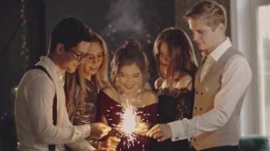 Kapalı portre arkadaşları maytapları ellerinde tutuyorlar. Çocuklar havai fişek sallayarak, yılbaşı ya da Noel arifesinde eğlenerek kutluyorlar. Mutlu bir grup insan akşamları eğleniyor..