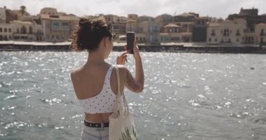 Asyalı kadın Yunan şehrinin fotoğrafını çekiyor. Seyahat, turizm konsepti. Çekimler RED 4k, 10 bit renk.