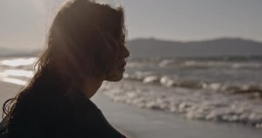 Dramatik kadın portresi, rüzgarlı plaj, sinema kamerasında çekilen, dağların ve okyanusun arka planına karşı siyah takım elbiseli zalim kız. Omzuna dokunan güzel bir esmer. Sanat evi kavramı ve...