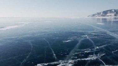 Donmuş Baykal Gölü, hava manzaralı. Pürüzsüz buzla güzel bir kış manzarası. Rusya 'nın ünlü doğal simgesi. Derin çatlakları olan mavi şeffaf buz, donmuş bir göl manzarası..