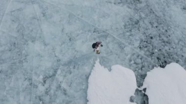 Baykal Gölü 'nde kayan adamın buzla kaplı görüntüsü. Erkek sporcu, soğuk havada, gökyüzü ve bulutlar gölün güzel buzlu yüzeyine yansıyor..