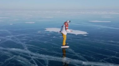 Baykal Gölü 'nde kayan adamın buzla kaplı görüntüsü. Erkek sporcu, soğuk havada, gökyüzü ve bulutlar gölün güzel buzlu yüzeyine yansıyor..