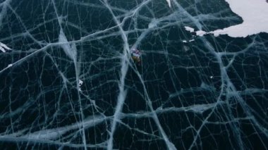 Baykal Gölü 'nde kayan adamın buzla kaplı görüntüsü. Erkek sporcu, soğuk havada, gökyüzü ve bulutlar gölün güzel buzlu yüzeyine yansıyor..