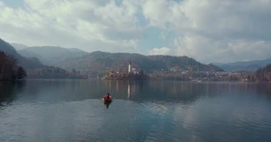 Yaz tatili izolasyonu. Puslu günbatımında Bled Gölü 'nde teknede oturan şapkalı romantik kadın. Seyahat macerası sırasında rahatlayan bir kızın arka görüntüsü. Özgürlük, deneyim, gezi konsepti.