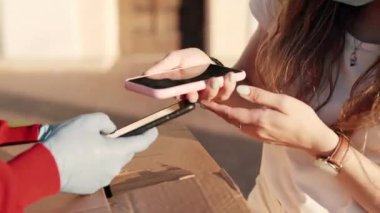 NFC teknolojisini telefon ve kredi kartıyla kullanan güzel bir müşteri. Coronavirus karantina salgınından sonra kız öğrencilerle irtibatsız bir ödeme..