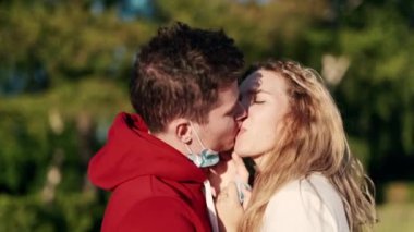 Günbatımında birbirlerine aşık genç bir çift tıbbi koruyucu maskeler takıyor. Gençler koronavirüsü görmezden geliyor karantina sosyal mesafeyi koruyor ve covid-19 hastalığının yayılmasını engelliyor. Covid sağlık konsepti.