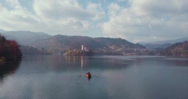 Yaz tatili izolasyonu. Puslu günbatımında Bled Gölü 'nde teknede oturan şapkalı romantik kadın. Seyahat macerası sırasında rahatlayan bir kızın arka görüntüsü. Özgürlük, deneyim, gezi konsepti.