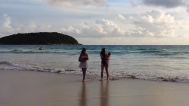 Deniz kenarında küçük çocukları olan genç anneler, gün batımında çocuklarıyla kumsalda olan genç kadınlar.