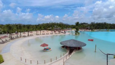 Havuzun yanındaki dinlenme alanında şemsiyeler ve güneşlikler var. Slaytlı ve derin havuzlu su parkı